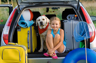 a dog sand girl sitting in the back of a packed car